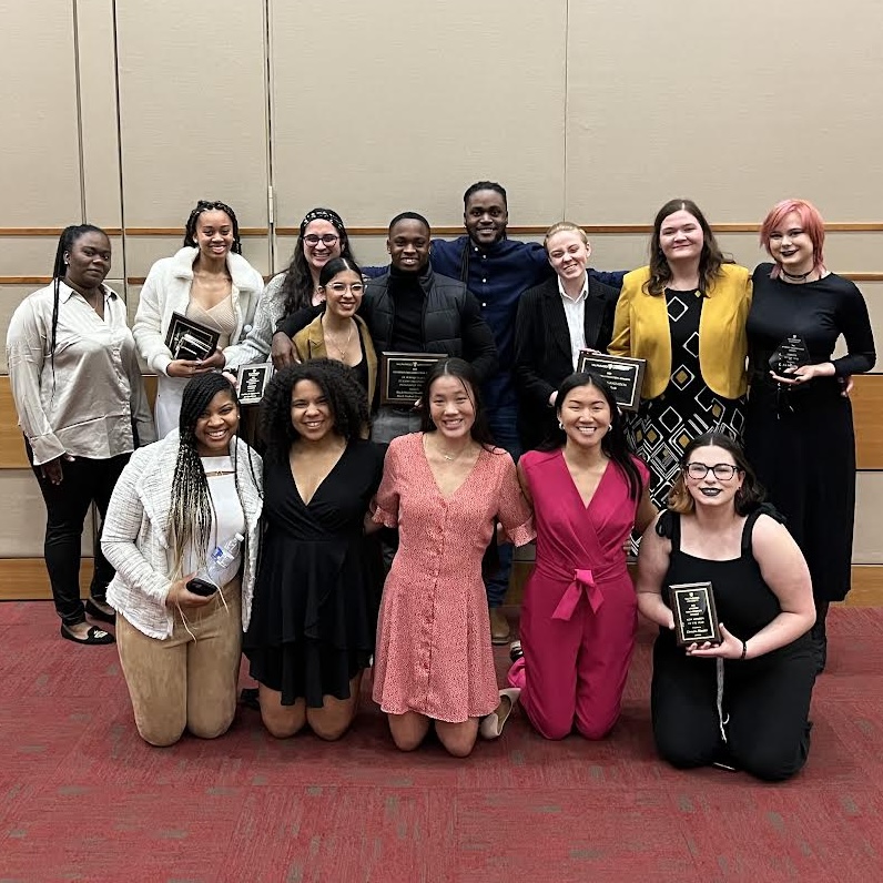 Valpo Alliance President DeMira Hunter '25 poses for a photo among a larger group of students, an award plaque in their hands.
