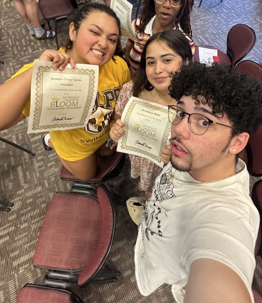 Jazzy Soria Gonzalez '24 smiles in a selfie-style photo with two other Valpo students, holding up personalized certificates from Valparaiso University's Bloom Scholars Program.