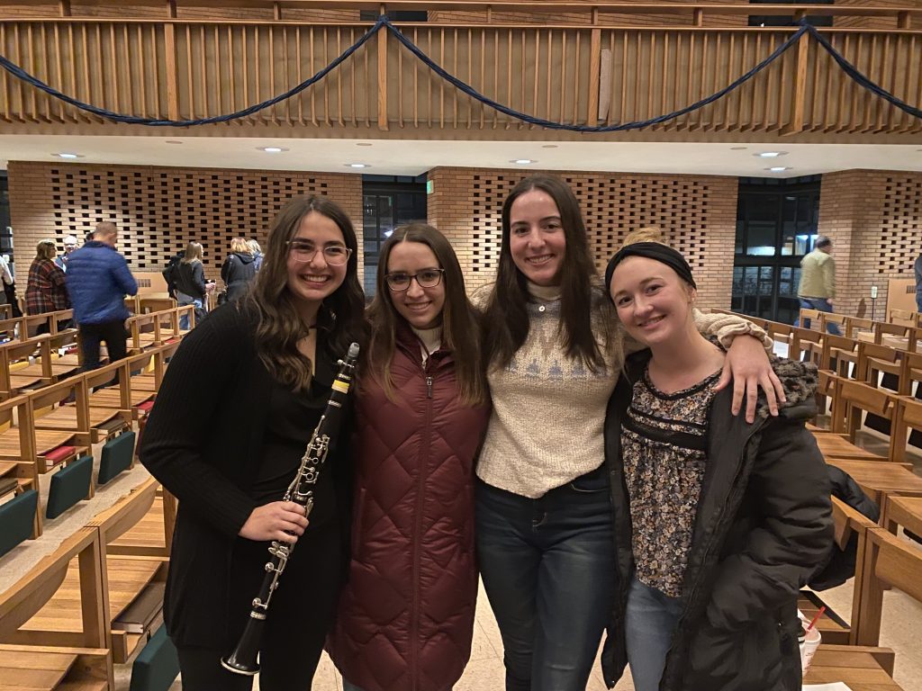 Ashley Velasquez ’25 stands with three friends in Valparaiso University's Chapel of the Resurrection, smiling and holding a clarinet. 