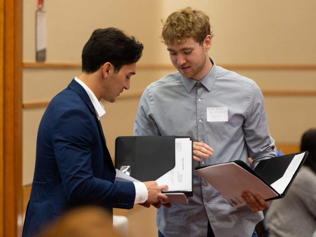 Two men going through their binders looking over the papers inside.