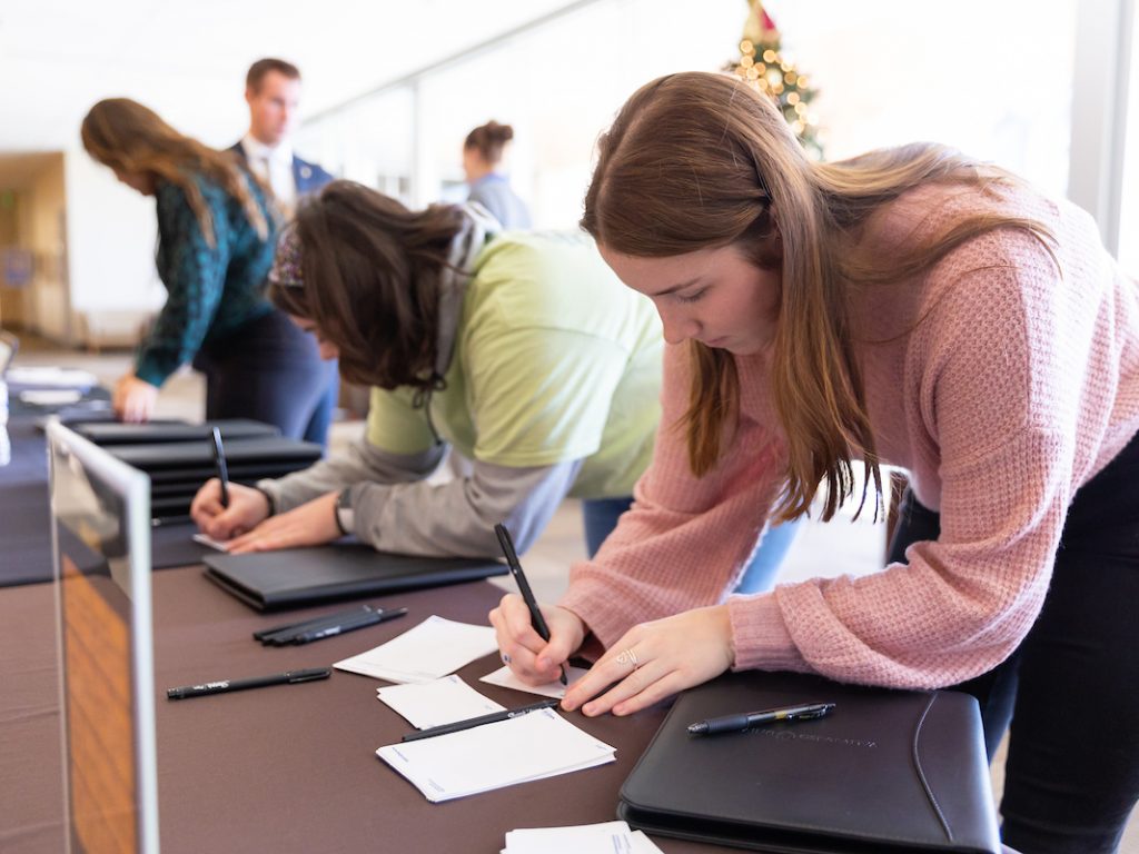 Two Students filling out a form at a table.