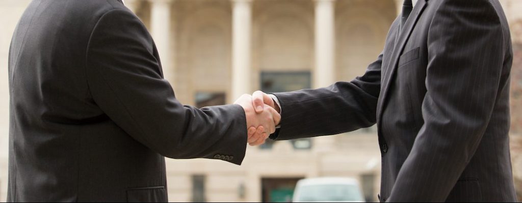 Two men in business attire shaking hands.