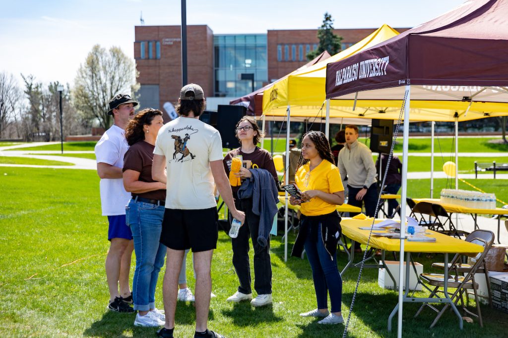 Valparaiso University event outdoors with tents and a group of people having a conversation..