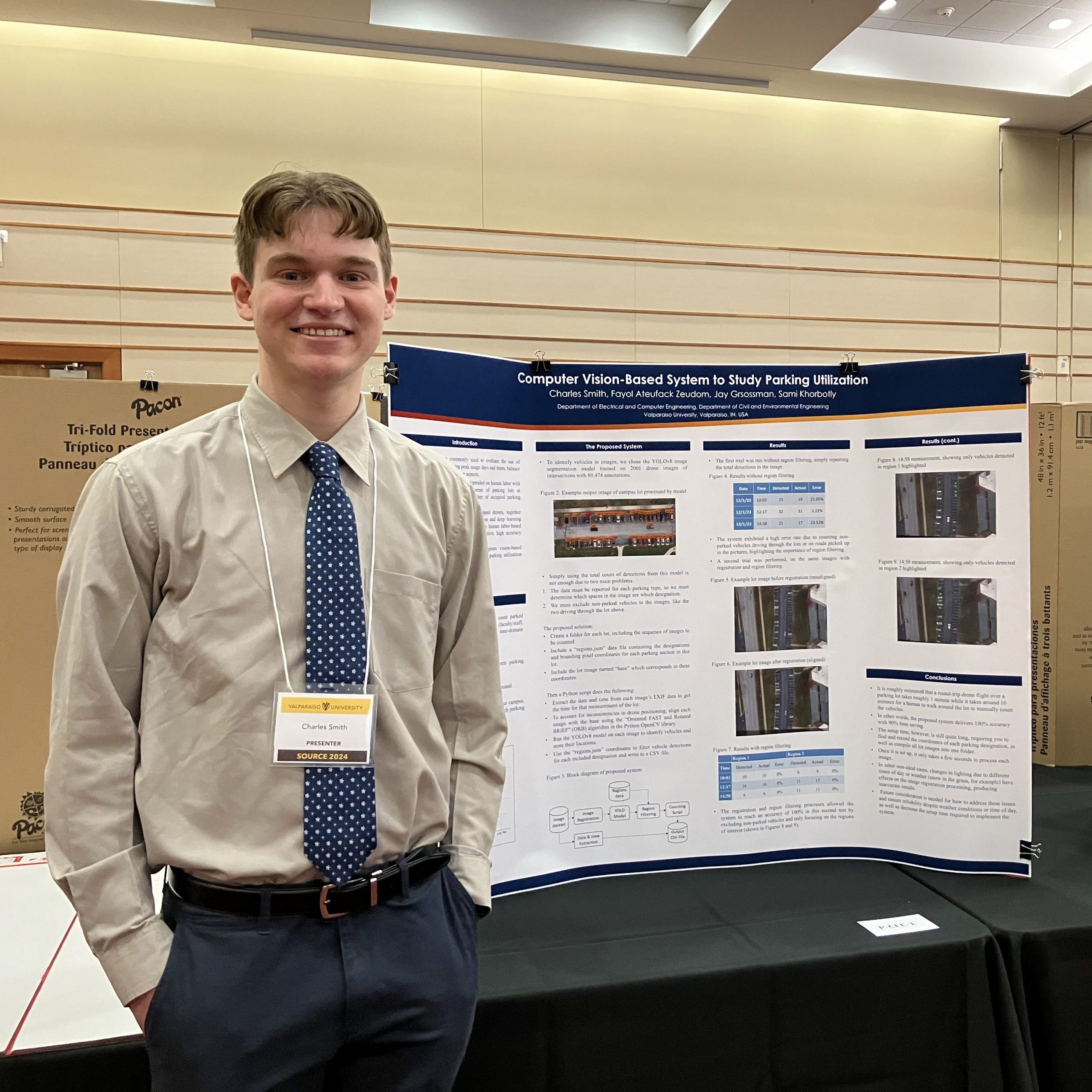Charles Smith ’25 smiling and standing by his poster presentation at SOURCE 2024.