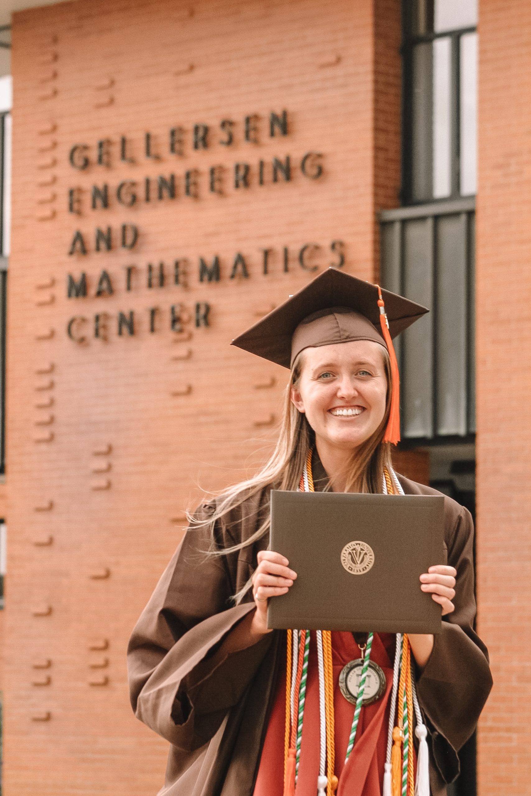 allie Lyon ’20 smiling while wearing Commencement regalia and holding her diploma.