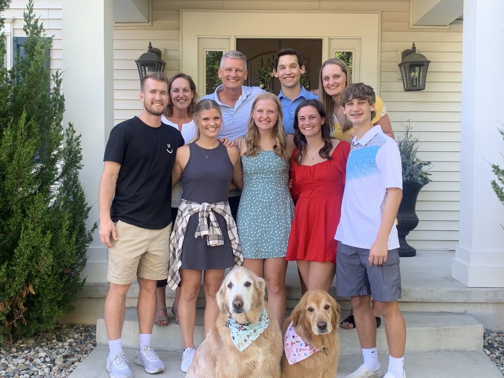 Valparaiso University student-athlete Emma Hickey '26 poses with family and two dogs on a front porch.