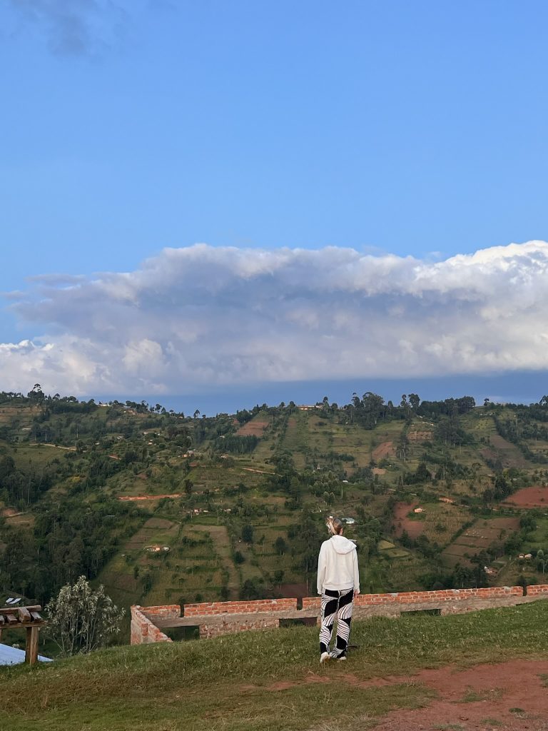 Cailey Rooker '24 with her back turned, looking out over a Kenyan hillside with mountains in the background.