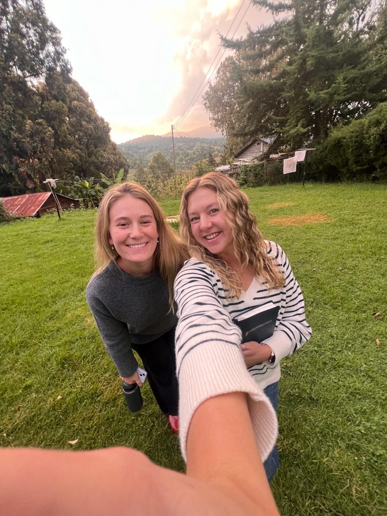 Valparaiso University alumni Cailey Rooker '24 and Rachel Yeager '24 posing for a photo, smiling with a Kenyan landscape in the background.