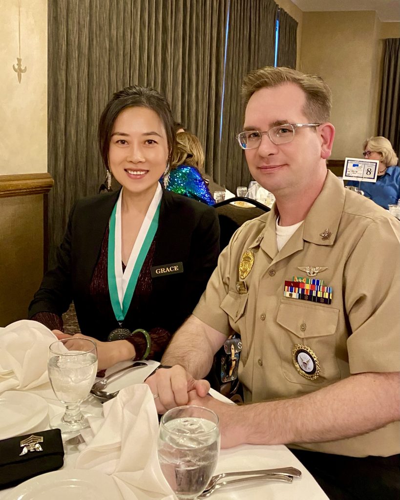 Valparaiso University business student Yingxin (Grace) Zhang ’25 smiles while sitting next to her husband dressed in Navy uniform.